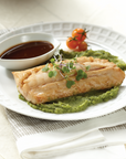 Plated dish of rockfish with green sauce and a side of cherry tomatoes on a white plate.
