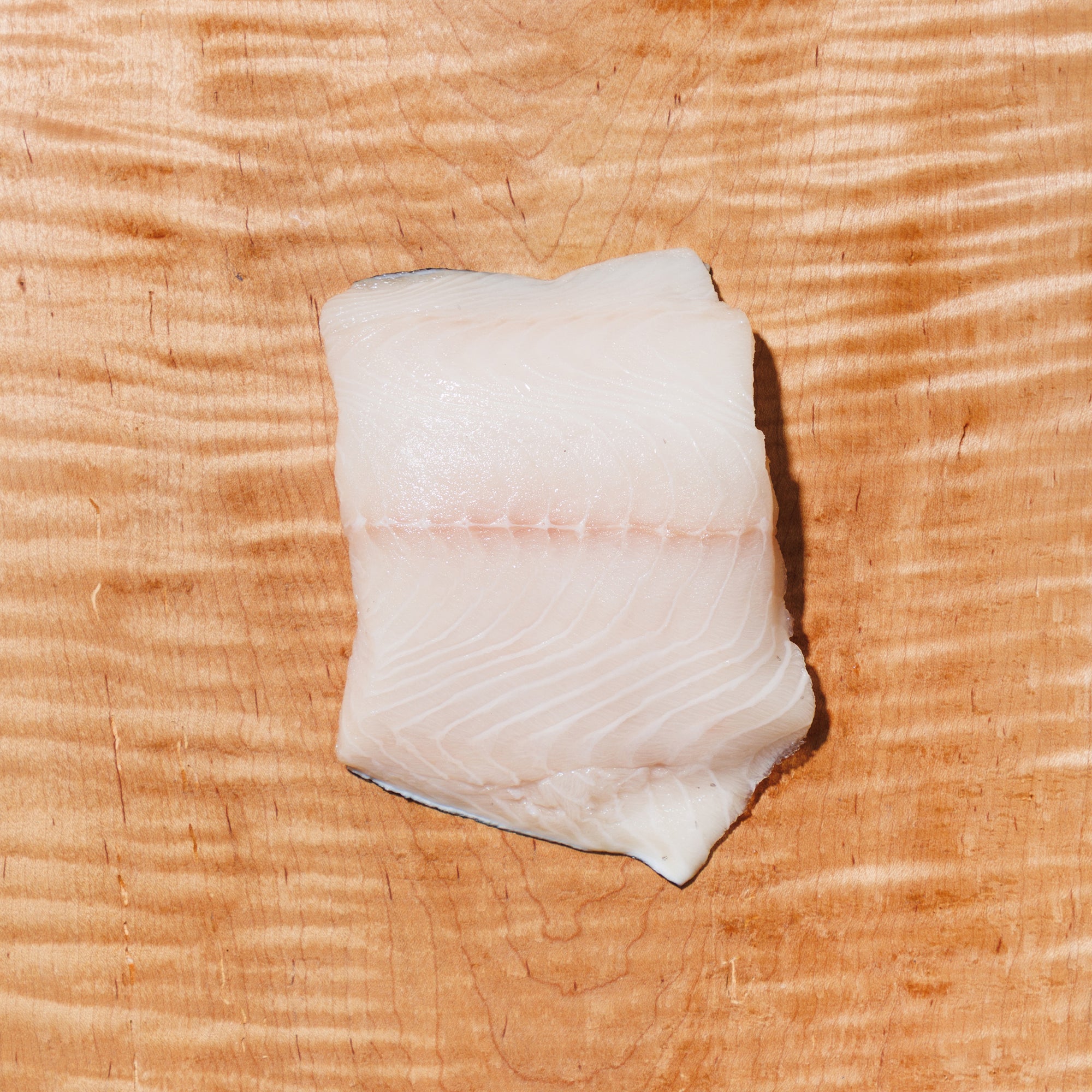 raw black cod on a wooden board