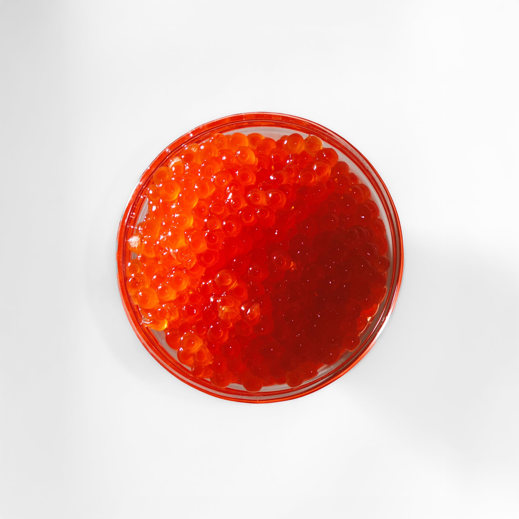 Red caviar in a glass bowl on a white background