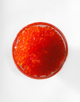 Red caviar in a glass bowl on a white background