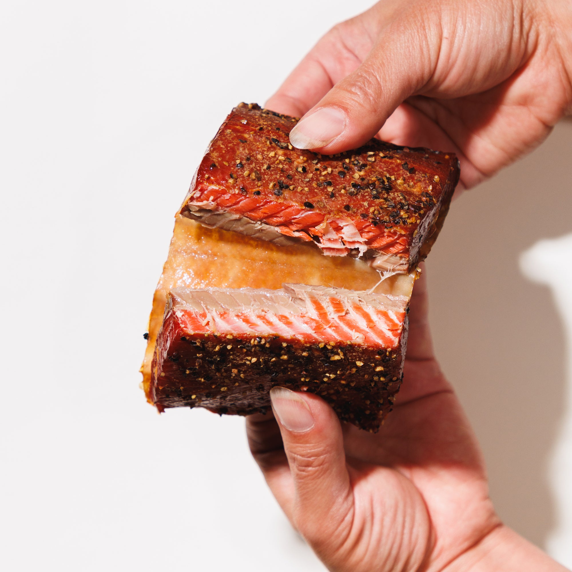 Hand holding garlic smoked salmon on a white background