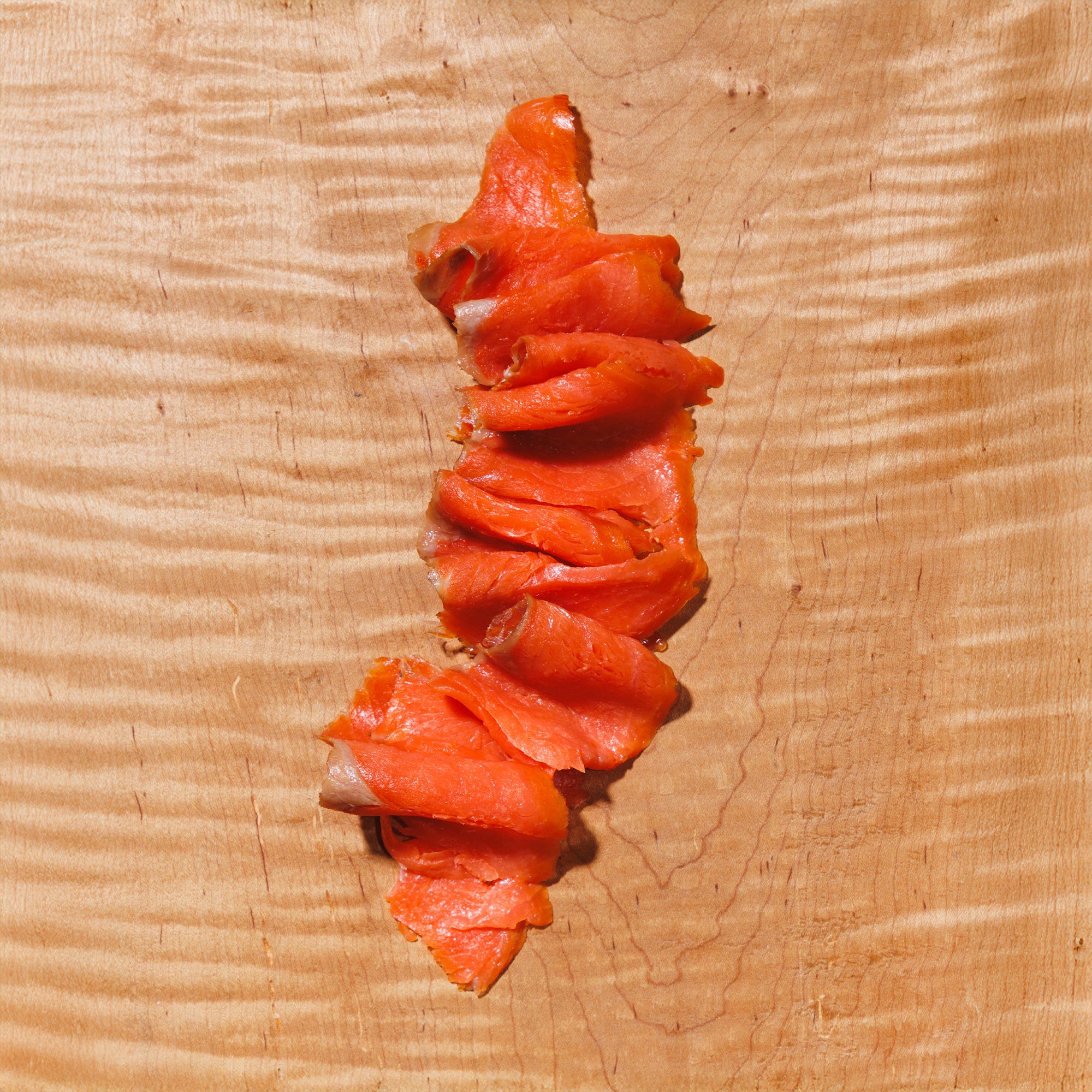 Sliced cold smoked nova salmon on a wooden background