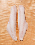 Two raw rockfish fillets on a wooden cutting board