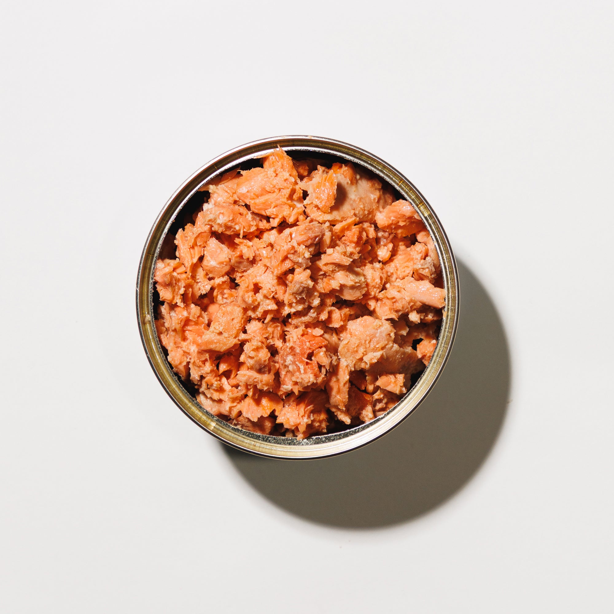 Open can of boneless skinless salmon on a white background