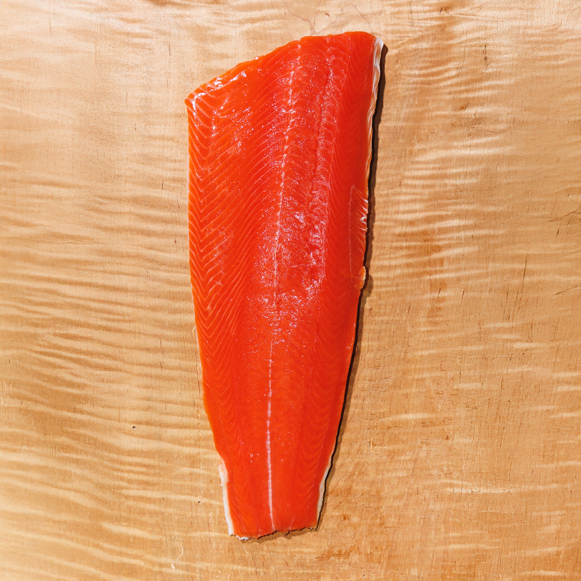 Raw sockeye salmon fillet on a wooden cutting board