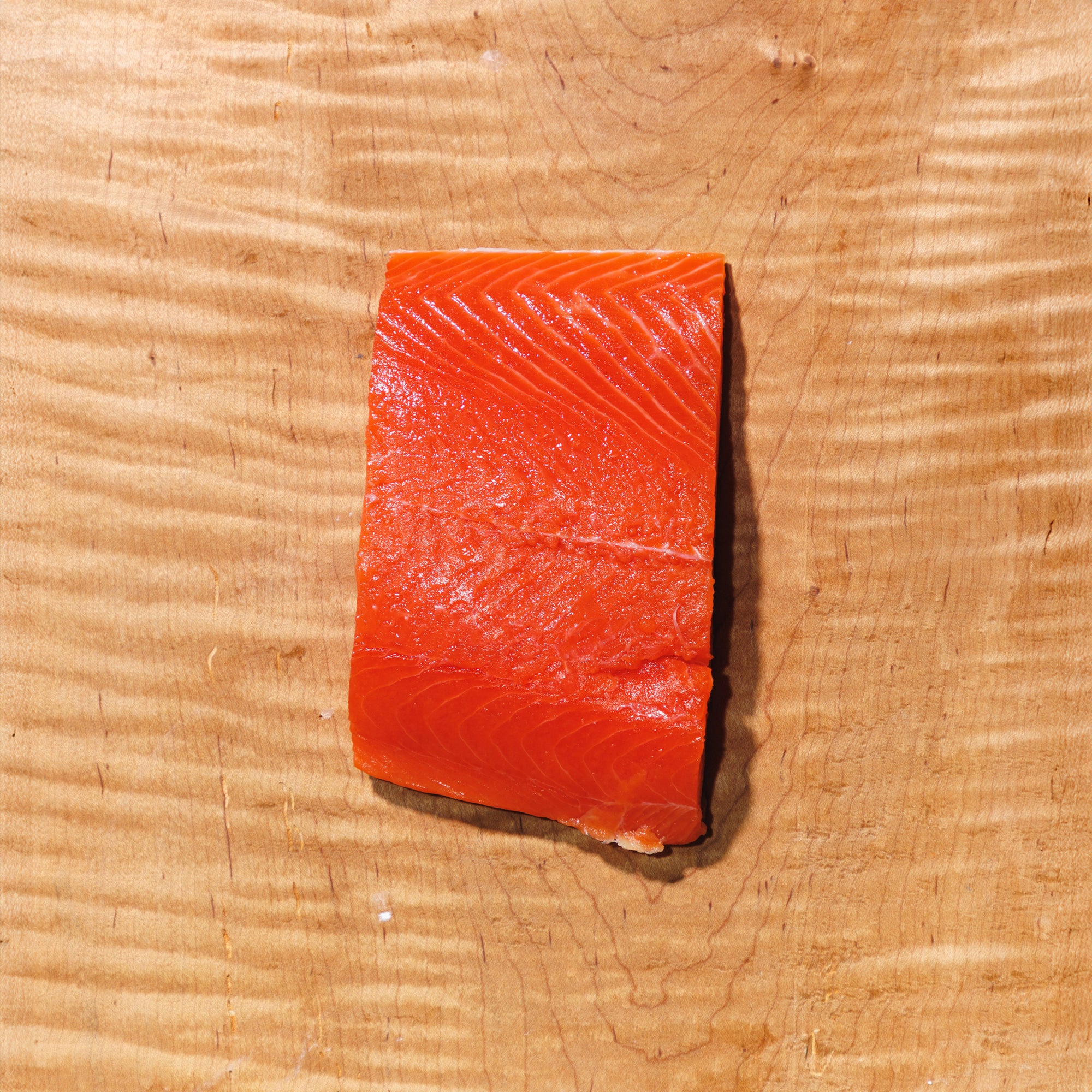 Raw sockeye salmon fillet on a wooden cutting board