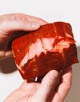 Hand holding a piece of smoked salmon with a white background