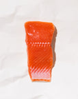 Raw coho salmon portion on a white paper background