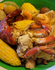Assorted seafood, including lobster, crab, shrimp, and corn, on a green plate.