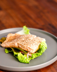 Keta Salmon portion on a bed of lettuce on a gray plate with a wooden background