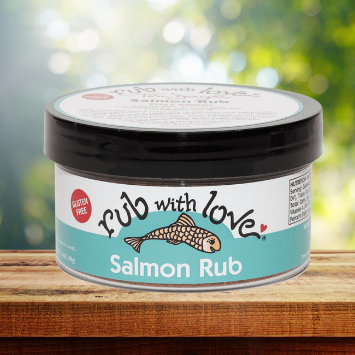 A container of Rub with Love salmon seasoning on a wooden board with a blurred natural background.