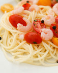 Spaghetti dish with tomatoes and shrimp on a white plate